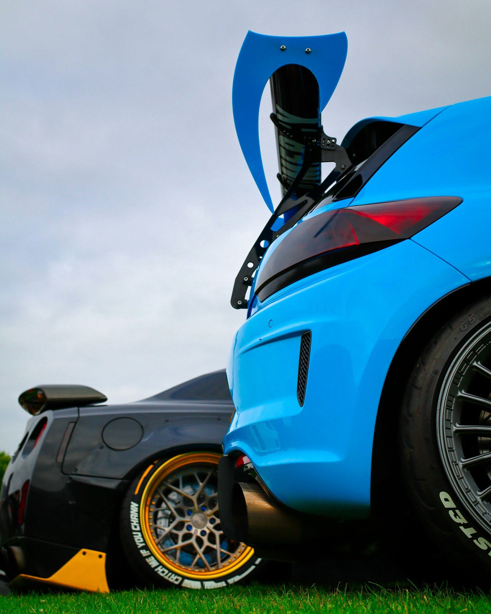 A blue sports car parked on top of a lush green field